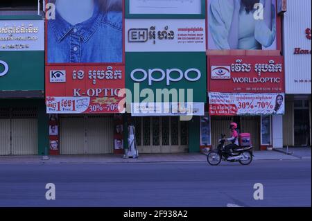 due to a recent outbreak of COVID - 19 at a garment factory, the Cambodian government has imposed a lockdown. here a food delivery driver drives down an empty street past closed stores to deliver food to Cambodians in quarantine who are not allowed to leave their street during the coronavirus pandemic. Stueng Meanchey, Phnom Penh, Cambodia. April 15th, 2021. © Kraig Lieb Stock Photo