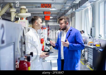 Engineer and technician discussing production process at factory Stock Photo