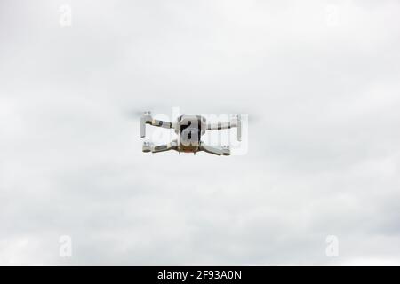 DJI Mini 2 drone in the air, pointing at the camera. With an overcast background. Stock Photo