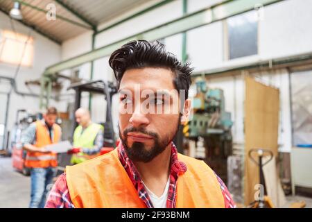 Warehouse workers in the warehouse of a metal construction factory with colleagues in the background Stock Photo