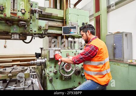 A worker as a machinist operates the coordinate drilling machine in the metal construction factory Stock Photo