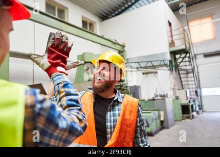 Two craftsmen or workers at the high five greeting for motivation in the factory Stock Photo