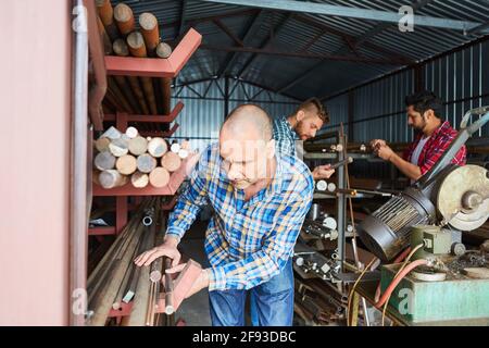 Craftsmen and metal workers in the material warehouse of a locksmith's shop or metal factory Stock Photo