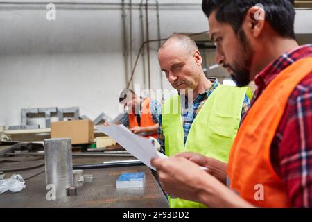 Two workers or skilled workers discuss an order in the locksmith workshop Stock Photo