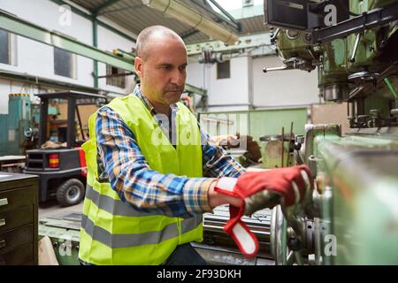 Metal worker operates a drill press in the production of the metal factory Stock Photo