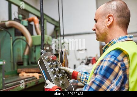 Worker in a metal factory controls a machine or a crane Stock Photo
