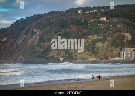 San Sebastian, Spain - March 15, 2021: Surfers on Zurriola Beach on a winter day in San Sebastian Stock Photo