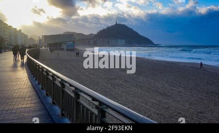 San Sebastian, Spain - Feb 19, 2021: Sunset over Monte Urgull from Zurriola beach Stock Photo