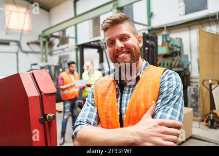Smiling young man as a warehouse worker or metal worker trainee in a warehouse Stock Photo