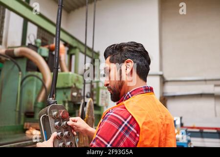 Young man as a worker at the control panel of a coordinate drilling machine or crane Stock Photo