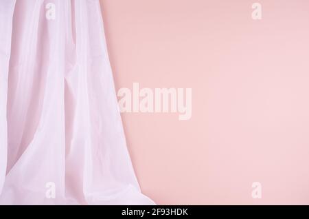 Delicate home decor with flow silk curtain on pastel pink wall. Mock up for portfolio, design or text. Stock Photo