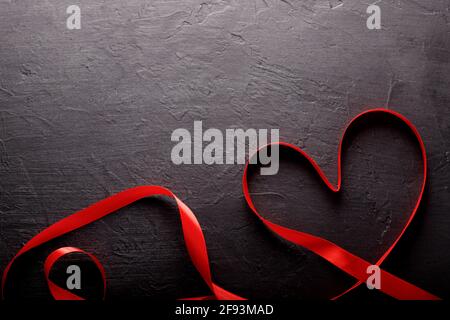 Happy Valentines Day. Red Ribbon on black stone background. Valentines Day concept Stock Photo
