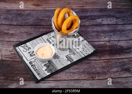 Oven baked breaded calamari rings, on serving board, on white stone