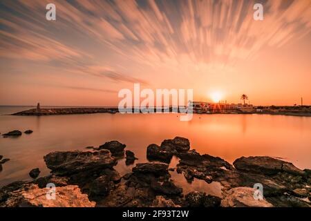 Beautiful shot of the mesmerizing sunset over the sea and a villa in the distance Stock Photo