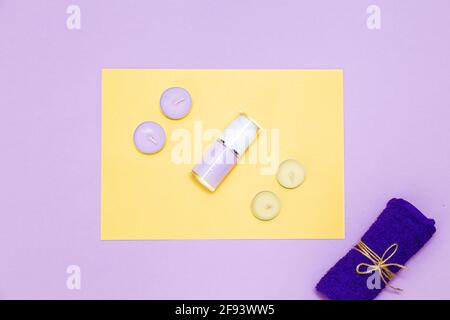 Scented candles, towel and lotion on a yellow and purple background. Top view, copy space. Spa concept, flat lay. Stock Photo