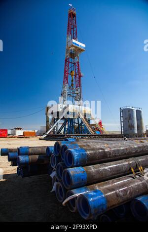 Aktobe region, Kazakhstan - May 04 2012: Extraction of oil from oil deposit in desert with rig. Drilling pipes and equipment on clear blue sky. Stock Photo