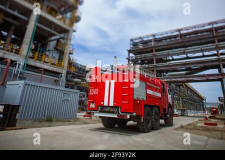 Atyrau, Kazakhstan - May 21 2012: Petrochemical plant. Red firetruck on grey pipelines background. Til-shift effect. Stock Photo