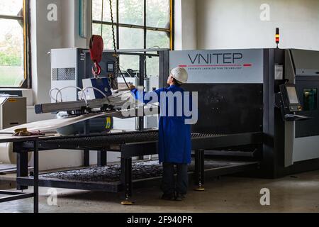 Uralsk (Oral)/Kazakhstan - May 05 2012: Modern CNC laser cutting maschine. Worker with crane hook put metal list on machine. Stock Photo