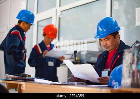 Modern logistic centre and warehouse. Three young operators in office. Aktobe, Kazakhstan. Right man in focus. Left people blurred. Stock Photo