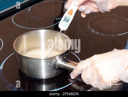 The temperature of the boiling syrup in the pan is measured with an electronic thermometer. Stock Photo