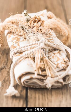 Rolled napkin or tea towel decorated with dried flowers and a ribbon, table decoration in natural colors on a wooden table, vertical photo with focus Stock Photo