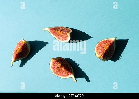 Cut pieces of fresh figs on a blue background with a bright shadow. Selective focus. Stock Photo