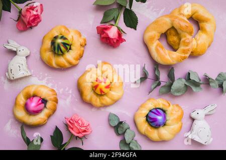 Homemade easter buns with colorful easter eggs on pink background, top view Stock Photo