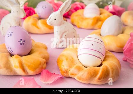 Homemade easter buns with colorful easter eggs on pinkish background Stock Photo