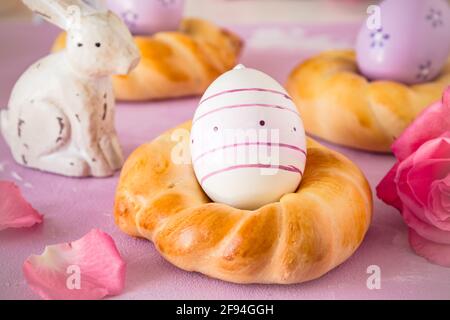 Homemade easter buns with colorful easter eggs on pinkish background Stock Photo