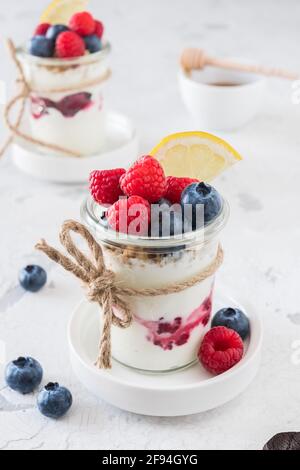 Yogurt with berries and cereals in a glass on white background, vertical Stock Photo