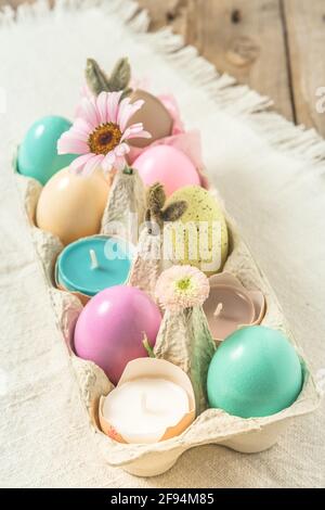 Box with pastel-colored easter eggs, candles in eggshells and spring flower blossoms as Easter decoration Stock Photo