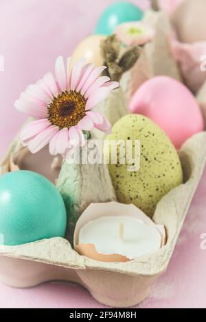 Box with pastel-colored easter eggs, candles in eggshell and spring flower blossoms as Easter decoration, vertical Stock Photo