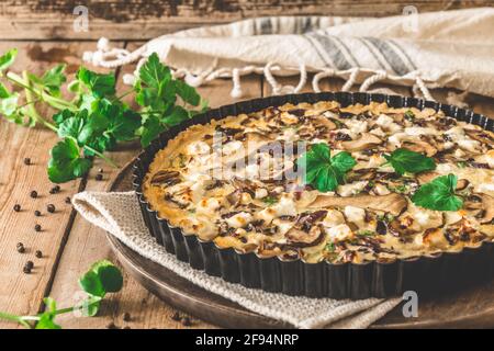 Vegetarian mushroom quiche with parsley on wooden table Stock Photo