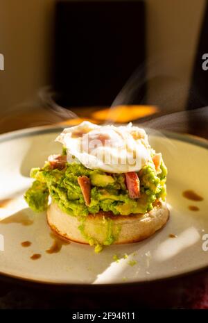 Crushed avocado and poached egg with ham pieces on a toasted crumpet for breakfast food UK Stock Photo