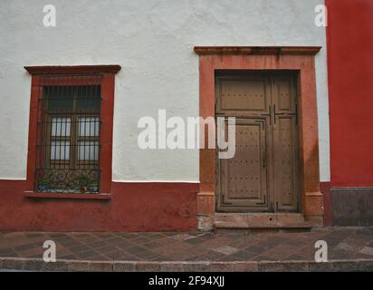 Colonial house facade with a Venetian stucco wall and a stone trimmed window and door in Santiago de Querétaro, Mexico. Stock Photo