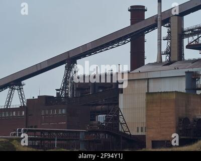 A tangle of buildings, scaffolding, heavy pipe lines and covered conveyors from the abandoned Redcar Steelworks industrial complex. Stock Photo