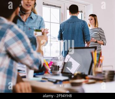 Couple of young friendly modern designers having a conversation near the window on a break. Stock Photo