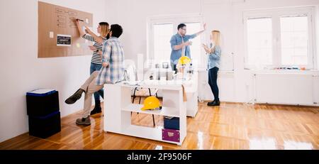 Group of four young focused successful business people sharing creative ideas for a break in the office while spending time together. Stock Photo