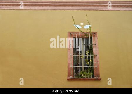 Colonial house facade with a stone trimmed window on a Venetian ochre stucco wall in the historic center of Santiago de Querétaro, Mexico. Stock Photo