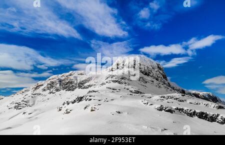 Panoramic view of a snow capped mountain peak with clouds and blue skies.  Stock Photo