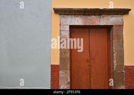 Colonial house facade with a stone trimmed wooden entrance door in Santiago de Querétaro, Mexico. Stock Photo