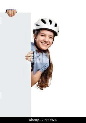 Young girl in white  bicycle helmet holds vertical white blank,Isolated on white Stock Photo