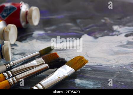 Oil paints and paint brushes on a palette close up. Stock Photo
