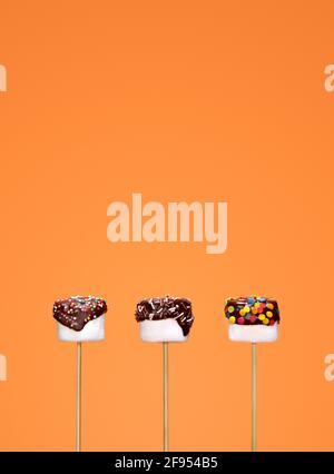 White marshmallow in chocolate on orange background. Stock Photo