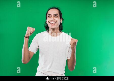handsome young man expressing happiness with clenched into fists and raised two hands Stock Photo