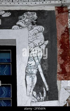 This mournful Renaissance armoured knight seems to stand partly behind the painted surround of a window in the sgraffito facade of House 28 in Kostelní námestí or Church Square at Prachatice, South Bohemia, Czechia / Czech Republic, which was richly decorated with sgraffito art when the property was remodelled in the mid-1500s.  With no. 29 next door, the house is traditionally linked to the early education of religious reformer and martyr Jan Hus (1369-1415). Stock Photo