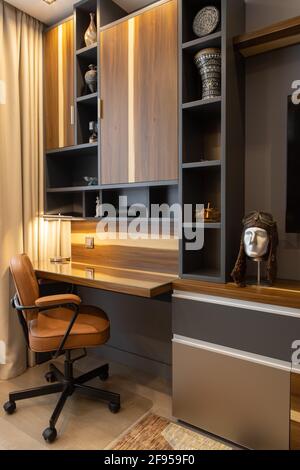 Modern, comfortable workplace, home office, brown tones. High quality furniture, table, shelves, chair with leather seat. Designer interior in style o Stock Photo