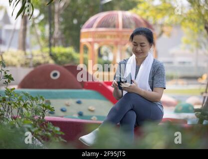 Senior woman in sport clothes receiving SMS on her mobile phone at the park Stock Photo