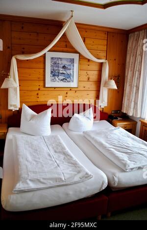 Traditional European style bedding arrangement. Two mattresses with white fitted sheet, duvet, duvet cover and plump feather pillows. Stock Photo
