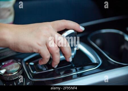 hand switches modes on the automatic transmission lever. close-up. no face. Driver woman hand holding automatic transmission or variable speed drive i Stock Photo